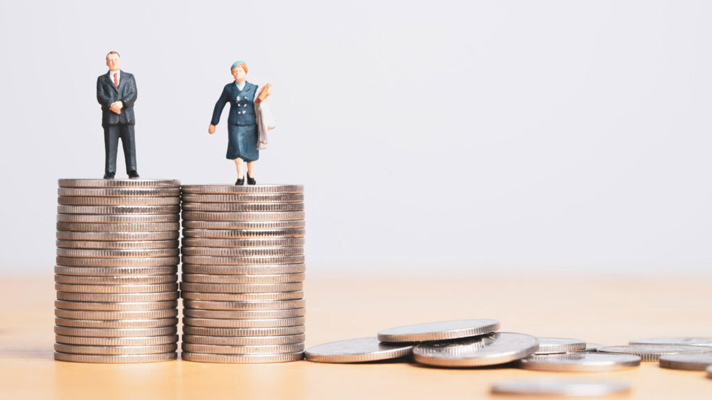 Miniature figures of businessman and businesswoman standing on equal coins stacking for equality of income and salary concept